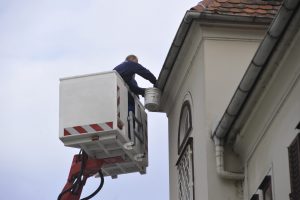 Arbeiter repariert Dachrinne von Hubsteiger.